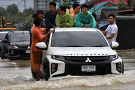 People hold onto a truck as it drives through flood waters