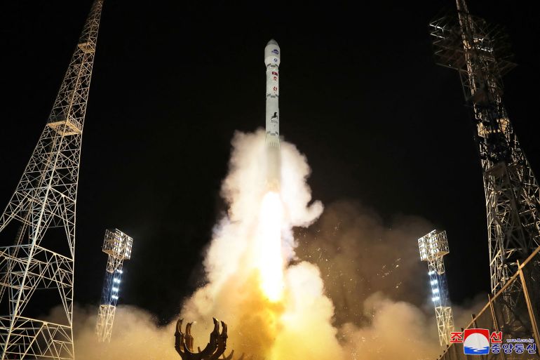 A rocket carrying North Korea's first spy satellite takes off in November. The launch is at night. There is lots of smoke and flames.