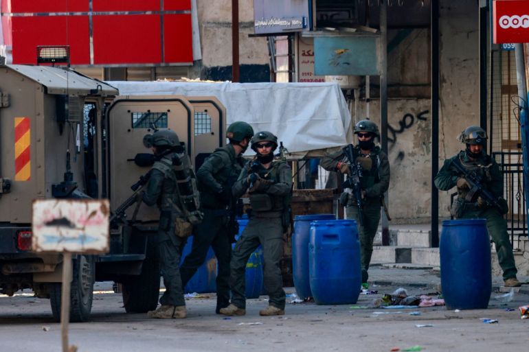 Israeli soldiers take position along a street during a raid in the Askar refugee camp, east of the occupied West Bank city of Nablus on December 31, 2023.