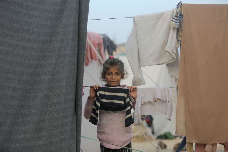 little girl looking at camera over clothesline hung between tents