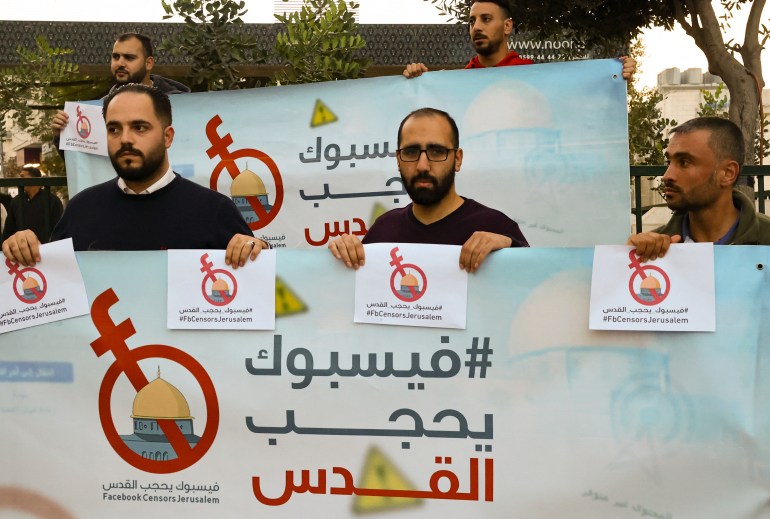 Palestinian activists and journalists hold banners with their campaign hashtag '#FBCensorsJerusalem' as they protest against what they consider censorship by the social media outlet Facebook of Palestinian content, in the occupied-West Bank city of Hebron, on November 24, 2021