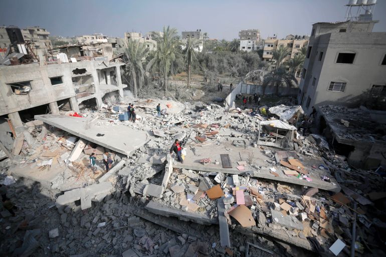 Palestinians try to collect usable items under the rubbles of a building, demolished following the Israeli attacks, in Deir al-Balah, Gaza on December 12