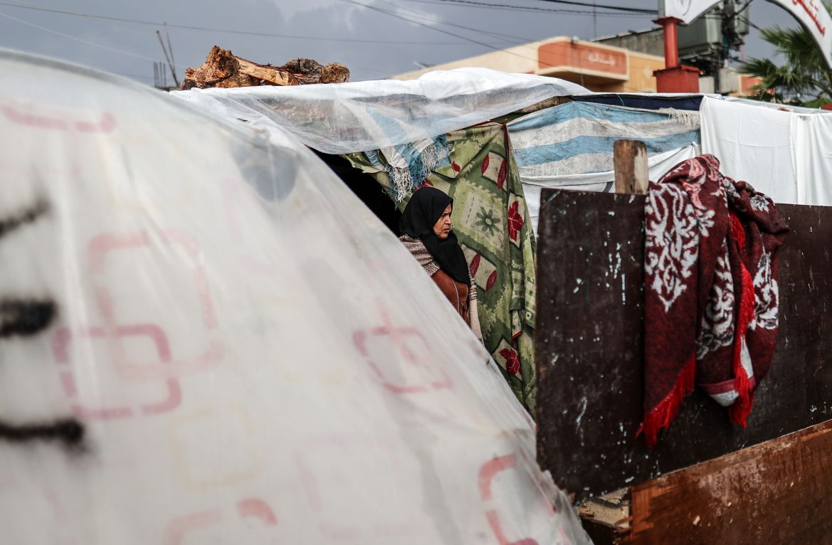 A woman is seen between makeshift tents as Palestinians who took shelter in the Aqsa Martyrs Hospital and its surroundings in Deir Al-Balah city of the Gaza are struggling with the strong winds, heavy rain and floods affecting the region amid Israeli attacks .