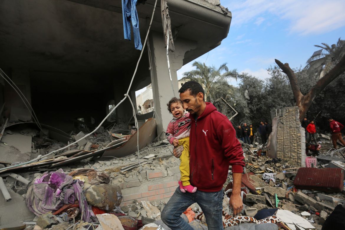 A man holding a crying child as search and rescue efforts for those trapped under rubble continue after Israeli airstrike hit civil residential area in al Maghazi refugee camp, Gaza on December 25