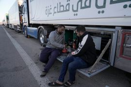 Humanitarian aid truck drivers drink tea as they wait to cross the Rafah border crossing to the Gaza Strip on Wednesday, November 29, 2023 [Amr Nabil/AP Photo]