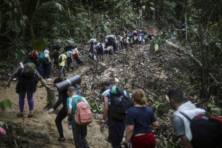 A line of migrants and asylum seekers wind their way up a dirt path through the rainforest of the Darien Gap.