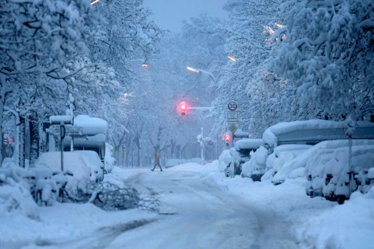 A man crosses a road early morning after heavy snow fall in Munich, Germany