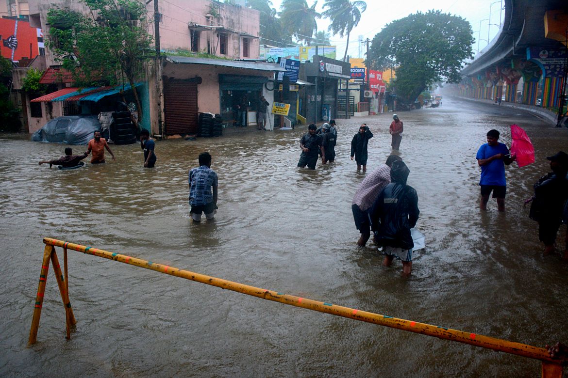 People wade through a flooded street following heavy rains along the Bay of Bengal coast in Chennai, India, Monday, Dec.4