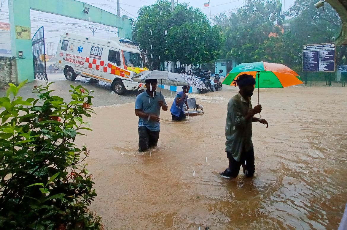 People walk outside the Tambaram Government Hospital flooded following heavy rains along the Bay of Bengal coast in Chennai