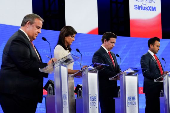 Four candidates — Chris Christie, Nikki Haley, Ron DeSantis and Vivek Ramaswamy — stand behind podiums on a debate stage in Alabama.