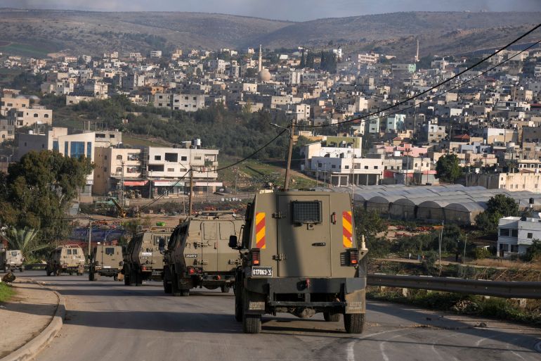 A convoy of Israeli army vehicles is seen during a military raid into Faraa refugee camp, West Bank, Friday, Dec. 8