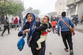 A Palestinian mother runs with her child from the site of Israeli bombardment in Rafah, southern Gaza Strip on December 20, 2023 [File: Fatima Shbair/AP]