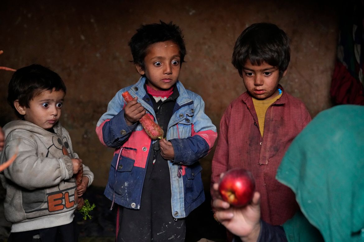 Three internally displaced children look with surprise at an apple that their mother brought home after begging, in a camp on the outskirts of Kabul, Afghanistan, Thursday, Feb 2