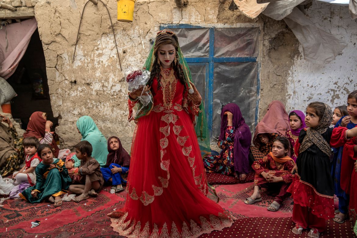Shamila, 15, from an internally displaced family, adjusts her wedding dress in an old mud house yard, on her wedding day, on the outskirts of Kabul, Afghanistan, Friday, May 19