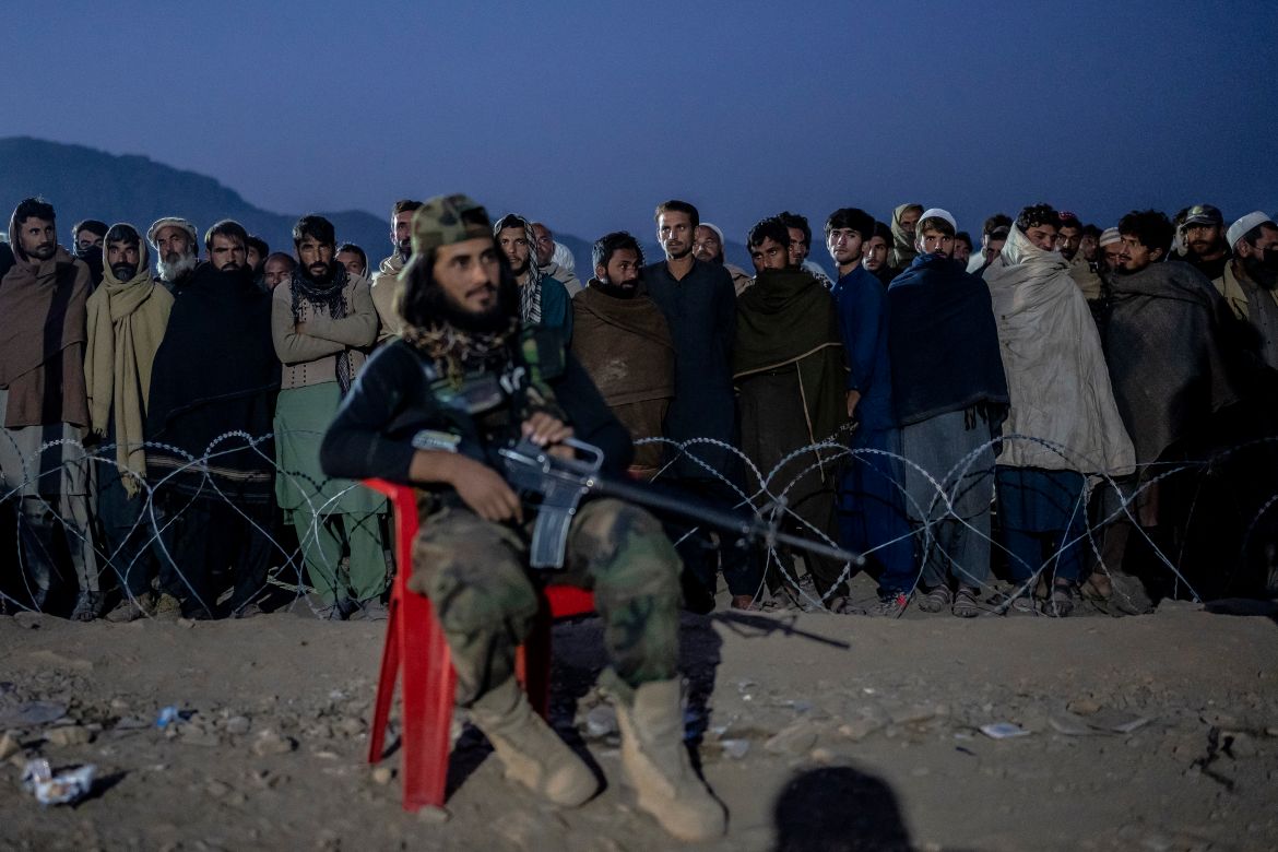 A Taliban fighter stands guard as Afghan refugees line up to register in a camp near the Pakistan-Afghanistan border in Torkham, Afghanistan, Saturday, Nov. 4,
