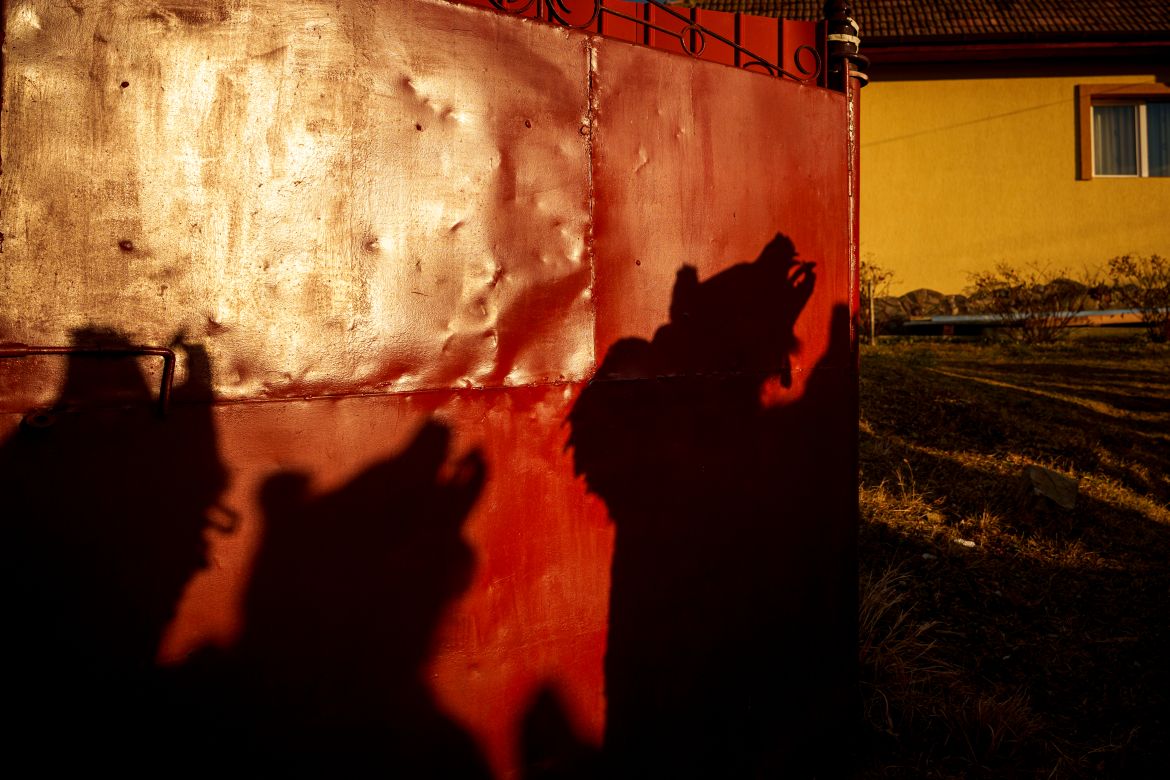 Members of the Sipoteni bear pack strike cast shadows on the gate of a village house in Vasieni, northern Romania, Tuesday, Dec. 26