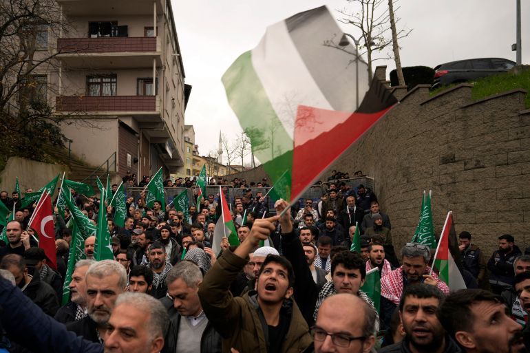 people wave palestinian flags while working through a street
