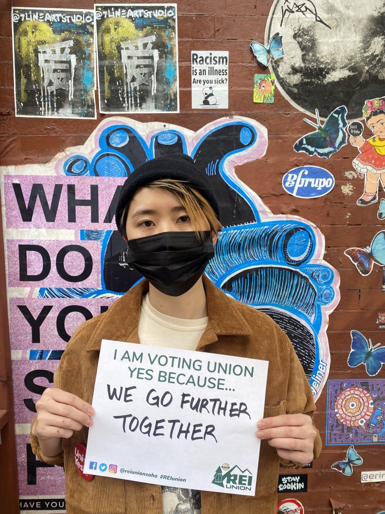 REI employee Claire Chang holding up a sign in favour of unionising 