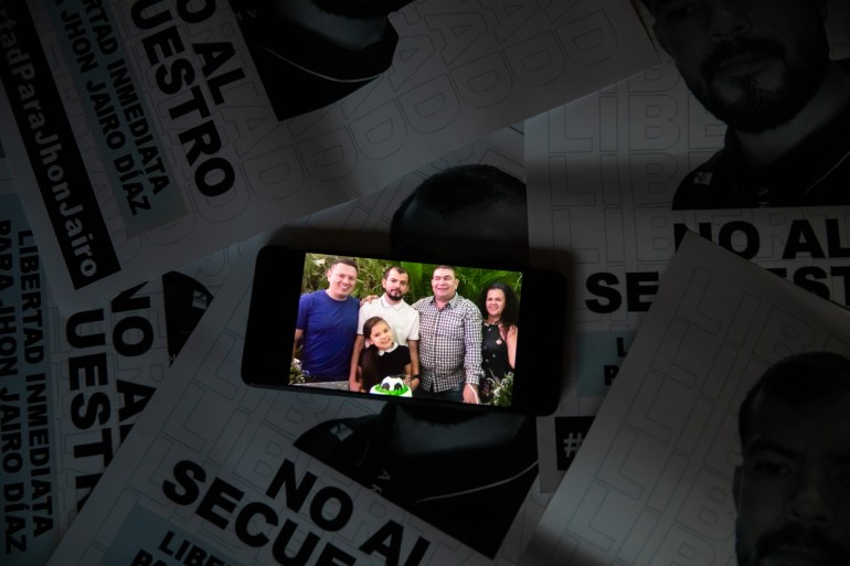 Auf einem Mobiltelefon ist ein Foto von Jhon Jairo Diaz im Kreise von Familienmitgliedern zu sehen.