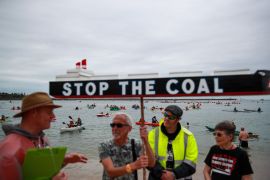 a man holds a sign that looks like a boat that says stop the coal