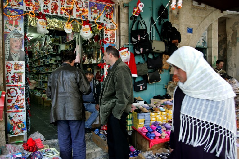 A poster of the late Palestinian leader Yasser Arafat vies for space with Christmas decorations for sale at a toy and novelty shop December 12, 2004 in the West Bank town of Bethlehem. 