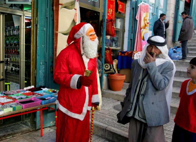 Hassan Abu Hillail, a 40-year-old Palestinian Christian shopkeeper, who dresses up as Santa Claus to try and drum up business, greets Palestinians passing his shop near the Church of the Nativity, the traditional birthplace of Jesus. 