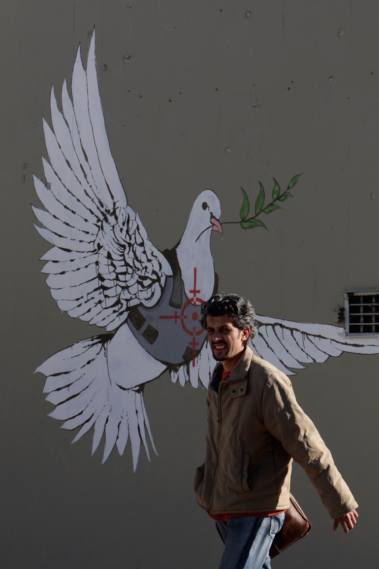 A Palestinian man passes a wall painting by elusive British graffiti artist Banksy.