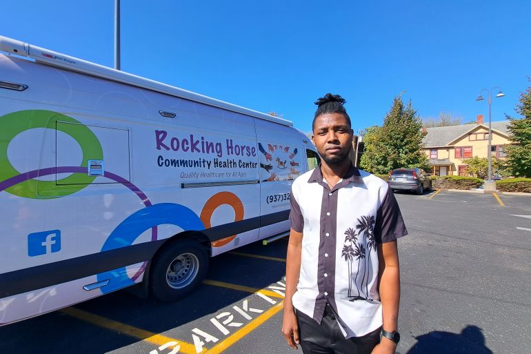 A man in a white-and-black collared shirt stands in front of a van for the Rocking Horse medical centre in Springfield, Ohio.