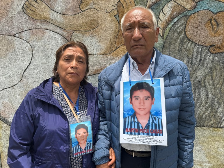 Javier Roca Obregón and his wife hold hands. Each of them wears a color photo around their neck featuring their missing son.