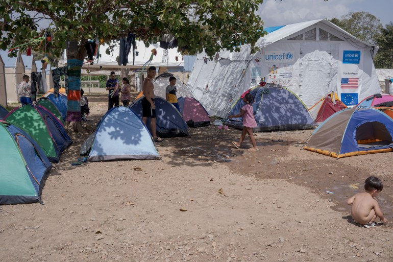 A cluster of personal tents sits outside in Panama, alongside a larger, white tent for UNICEF services. Children and adults are scattered among the tents.