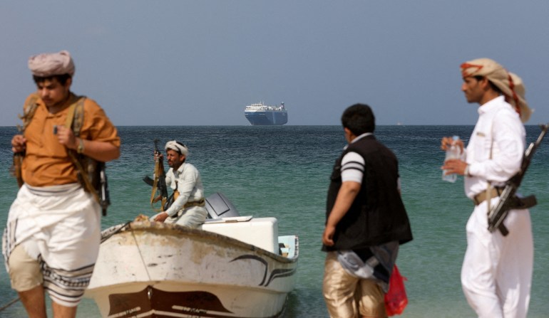 Armed men stand on the beach as the Galaxy Leader commercial ship, seized by Yemen's Houthis last month, is anchored off the coast of al-Salif, Yemen, December 5, 2023. [REUTERS/Khaled Abdullah/File]