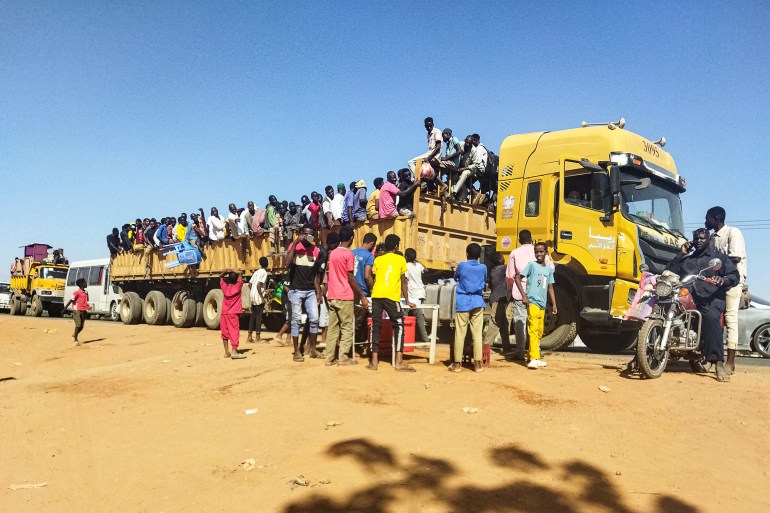 People displaced by the conflict in Sudan get on top of the back of a truck moving along a road in Wad Madani, the capital of al-Jazirah state, on December 16, 2023. [Photo by AFP]