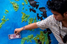A climate activist demanding reparations puts a mock-up money bill on a Philippine map showing the areas most affected by recent climate disasters, at a protest in Makati city, Metro Manila, the Philippines, on February 28, 2023 [Lisa Marie David/Reuters]