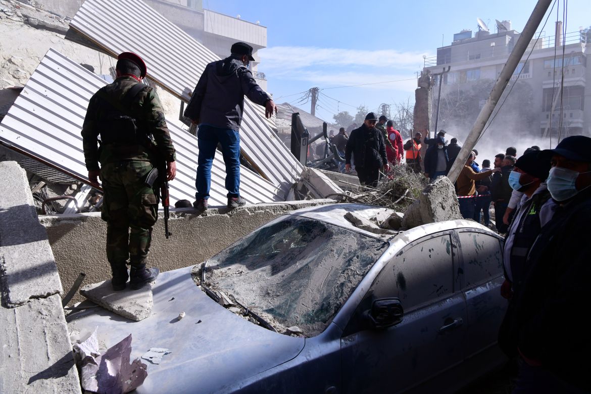 Soldiers and people check a damaged car at the site of residential building that was targeted in an alleged Israeli strike in Mezzah neighborhood, Damascus, Syria, 20 January