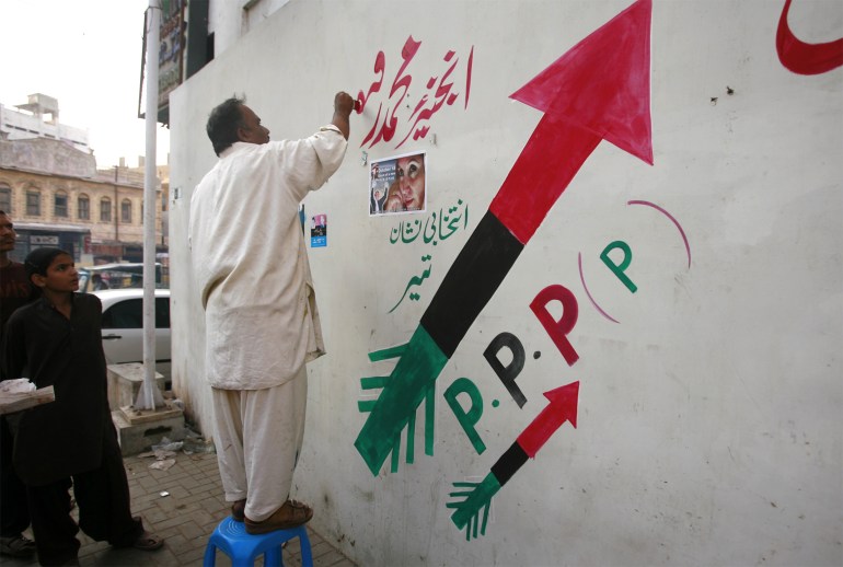 A man paints an arrow, the election symbol for Bhutto's Pakistan People's Party, ahead of the January general election in Karachi. 