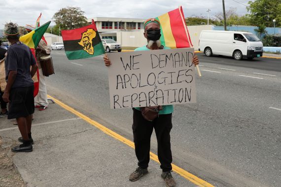 A protester holds a sign during a rally to demand that the United Kingdom make reparations for slavery, ahead of a visit to Jamaica by the Duke and Duchess of Cambridge as part of their tour of the Caribbean, outside the British High Commission, in Kingston, Jamaica March 22, 2022. REUTERS/Gilbert Bellamy