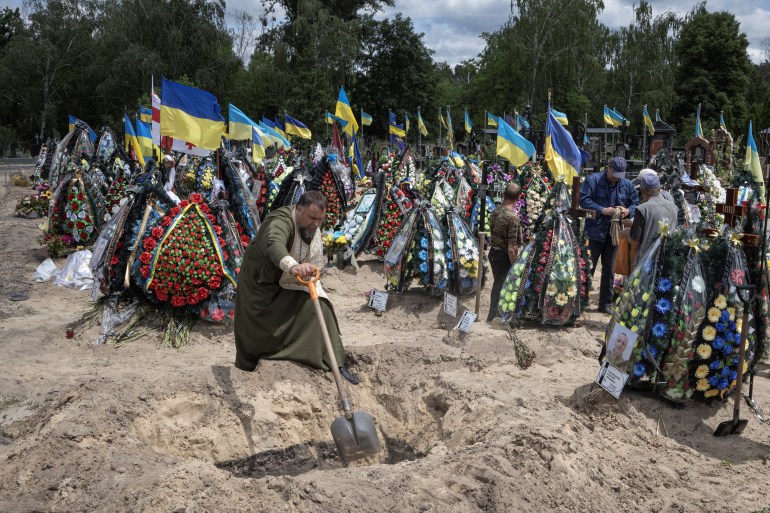 A priest shovels during a funeral for Ukrainian serviceman Mykhailo Tereshchenko who was killed in a fight during Russia's invasion in the Donbas region