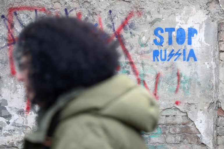 A pedestrian walks past an anti-Russian graffiti in a street in Tbilisi, Georgia