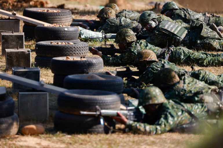 Taiwan national service soldiers showing their combat skills. They are lying on the ground behind piled up tyres with weapons at the ready