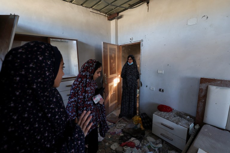 Palestinian women inspect the site of an Israeli strike on a house