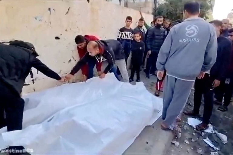 People cover bodies with a white sheet on a street following an airstrike on a house in Maghazi camp, Deir al-Balah, central Gaza,