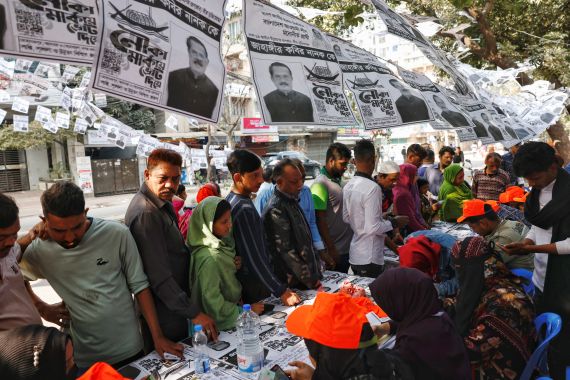 Anket görevlileri, 7 Ocak 2024'te Bangladeş'in Dhaka kentindeki Dhaka Konut Model Koleji oylama merkezinin önünde seçmenlerin oy pusulalarını almalarına yardımcı oluyor.