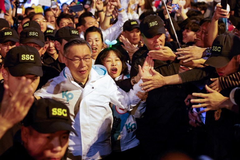 Ko Wen-je, candidato presidencial do Partido Popular de Taiwan (TPP).  Ele está vestindo uma jaqueta branca e andando por uma multidão de apoiadores 