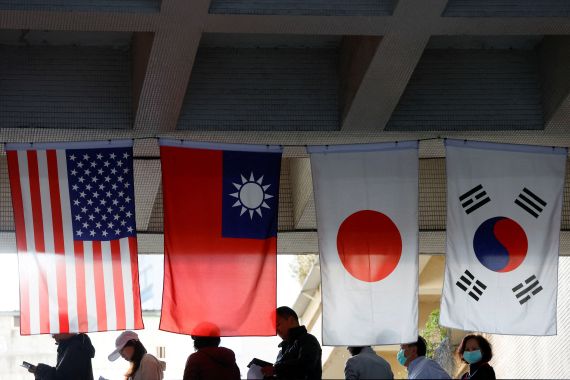 Tayvan'da insanlar ABD, Tayvan, Japonya ve Güney Kore bayrakları altında oy vermek için sıraya giriyor