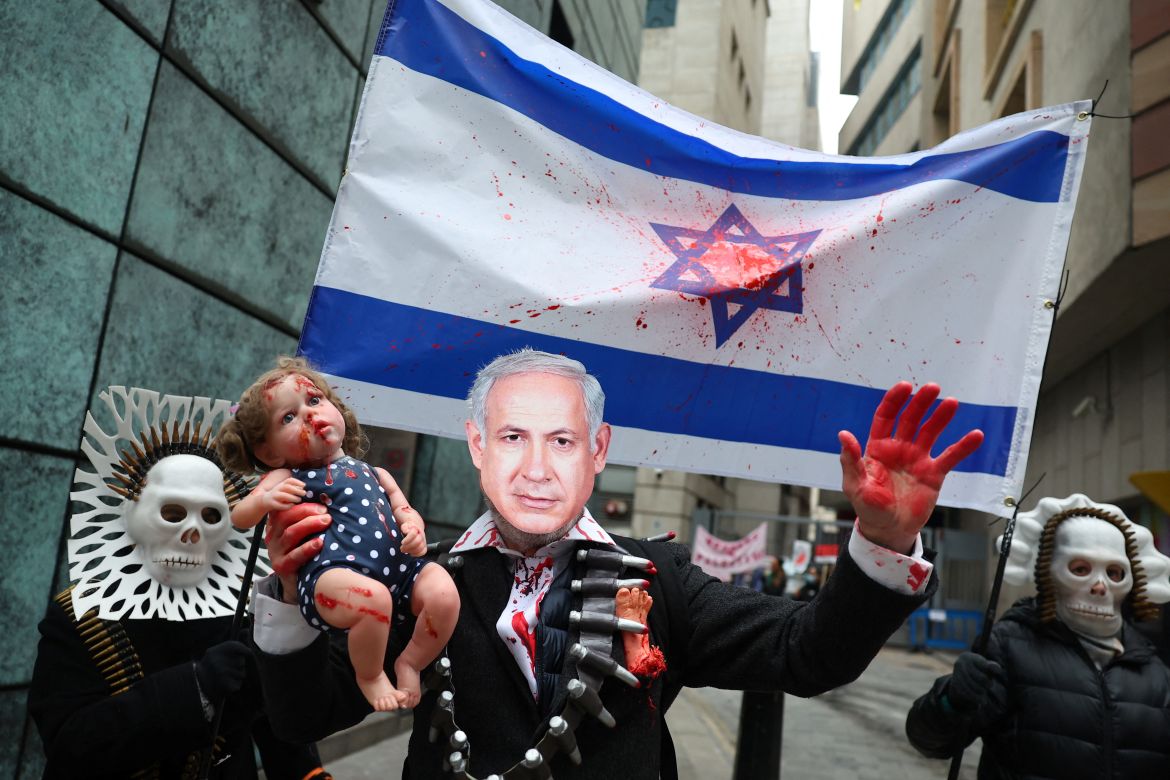A person, wearing a mask depicting Israeli Prime Minister Benjamin Netanyahu, holds a doll as people take part in a protest to mark 100 days since the start of a conflict between Israel and the Palestinian Islamist group Hamas during a "Ceasefire Now/Stop the War in Gaza" protest in London, Britain, January 13