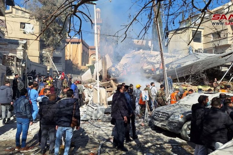 People inspect the damage at the site of the strike in Damascus