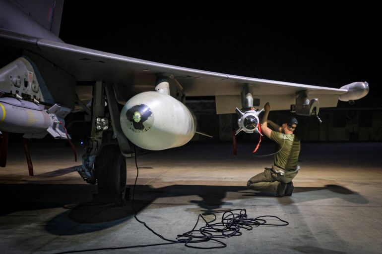 Um técnico de armas agachado sob a asa de um tufão da RAF antes dos ataques a alvos Houthi no Iêmen