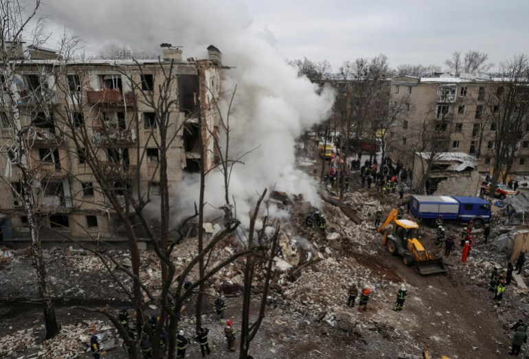 Residential apartments in Kharkiv badly damaged by Russian missiles. There are rescue workers on the rubble and an excavator. Clouds of white smoke are rising into the air.