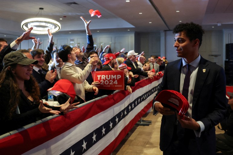 Behind a star-spangled barrier, Trump supporters throw MAGA hats and hold up signs in celebration of his primary victory.