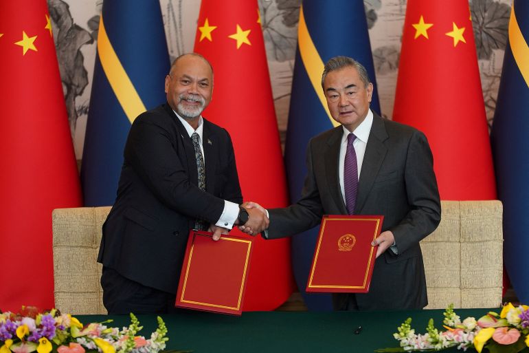 Chinese Foreign Minister Wang Yi, right and Minister of Foreign Affairs and Trade of Nauru Lionel Aingimea shake hands after signing a Joint Communique on the Resumption of Diplomatic Relations between China and Nauru